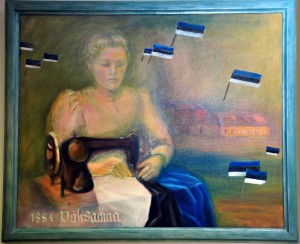 Emilie Beermann esimest sinimustvalget lippu õmblemas Põltsamaa kunstikooli direktori Ethel Hakkaja ja tema õpilaste tehtud maalil. Foto: Johannes Haab 